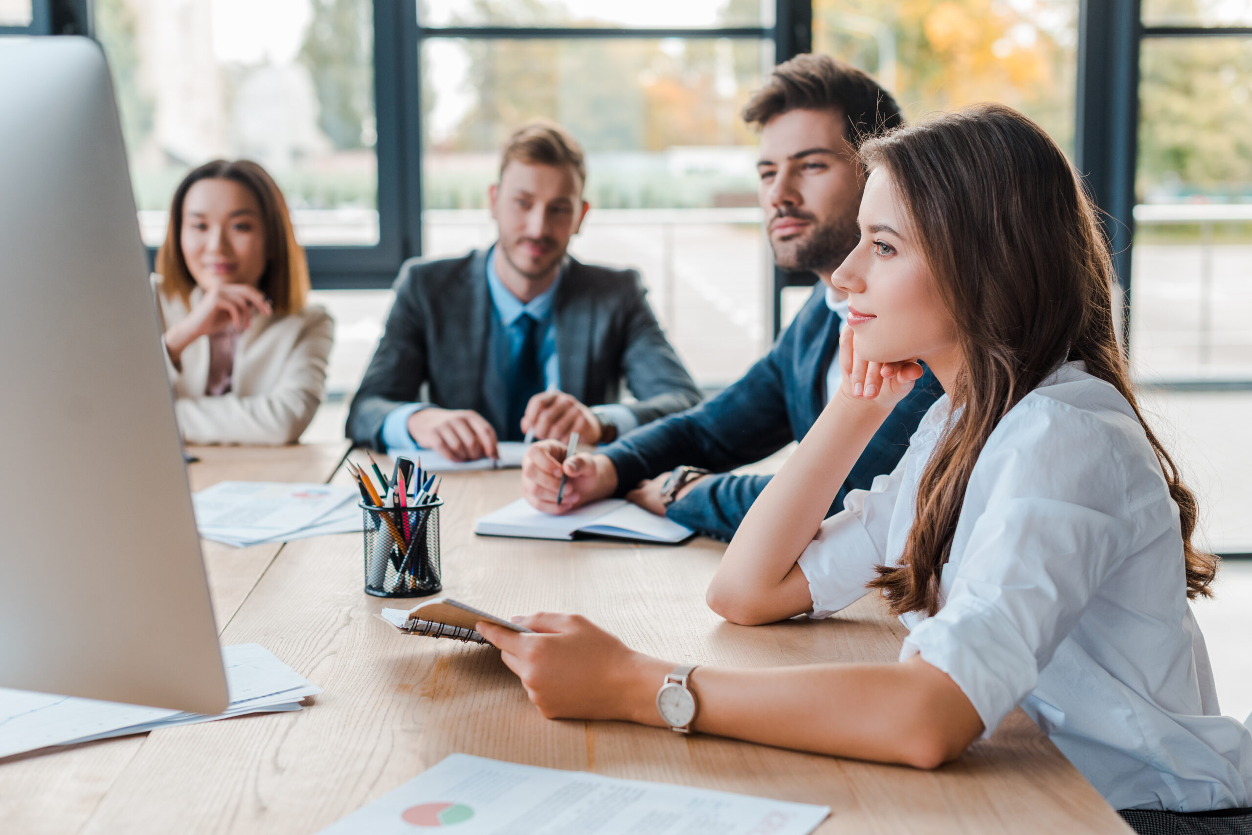 Kommunale Fachkräfte Team sitzen bei Inhouse-Webinar vor Bildschirm und arbeiten konzentriert zusammen.