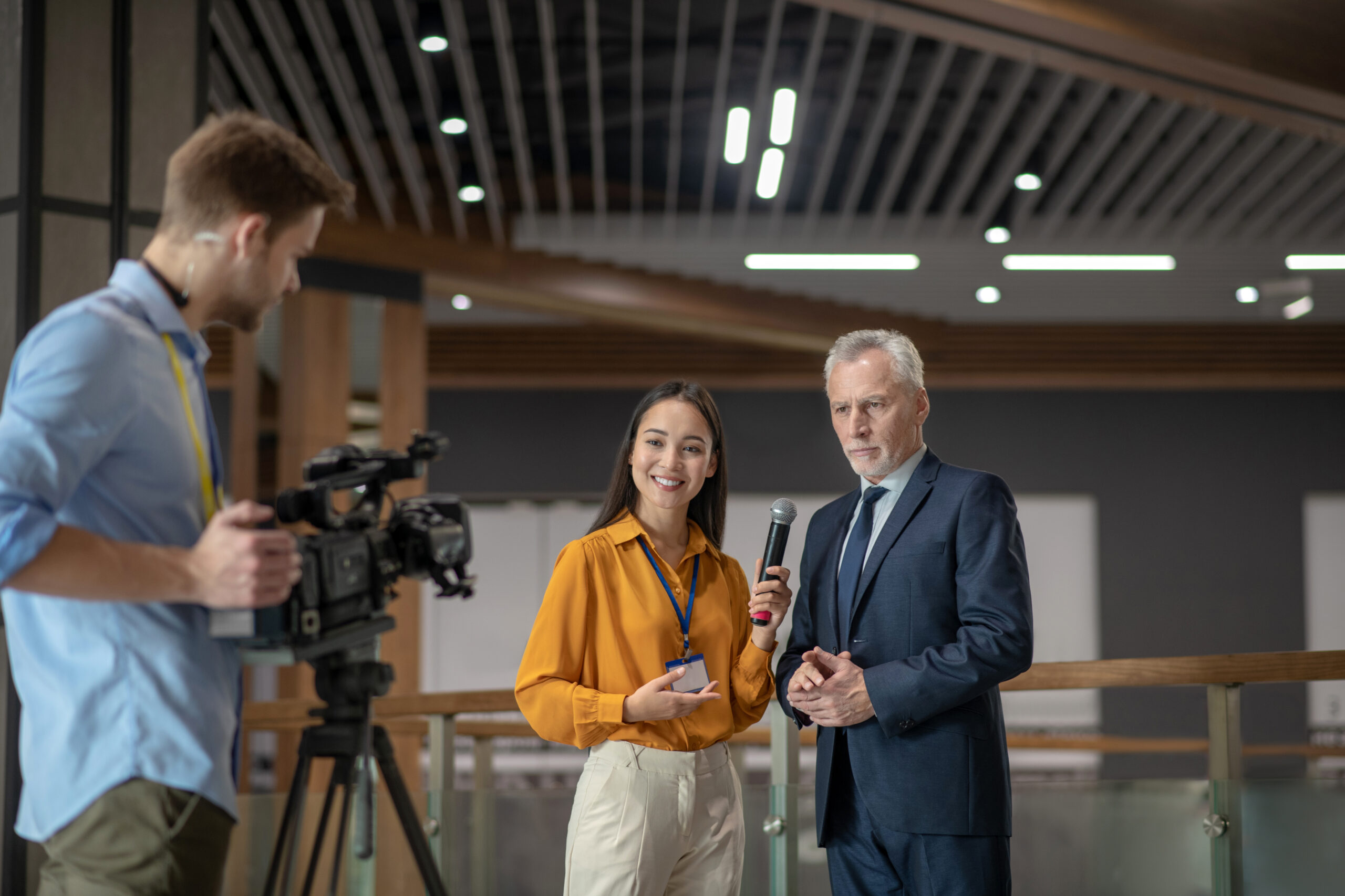 Journalistin interviewt Bürgermeister mit Mikrofon, Kameramann filmt Interview.