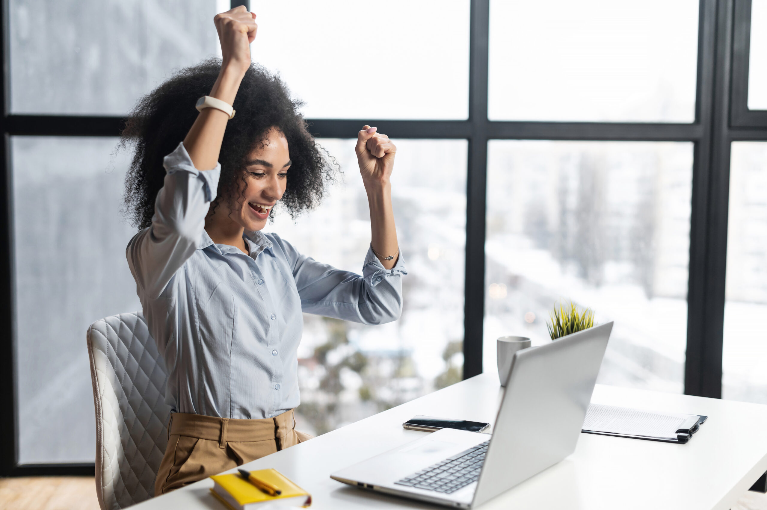 Frau jubelt am Schreibtisch über positive Nachrichten aus dem Newsletter auf dem Laptop.
