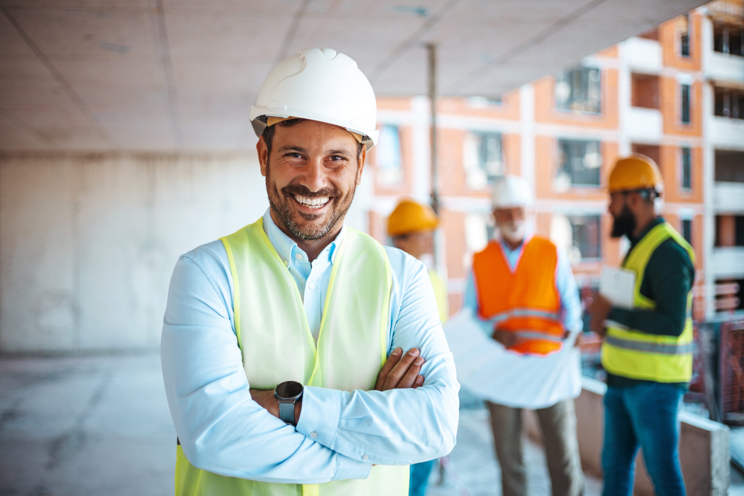 Lächelnder Bauleiter mit Helm und Weste auf Baustelle.