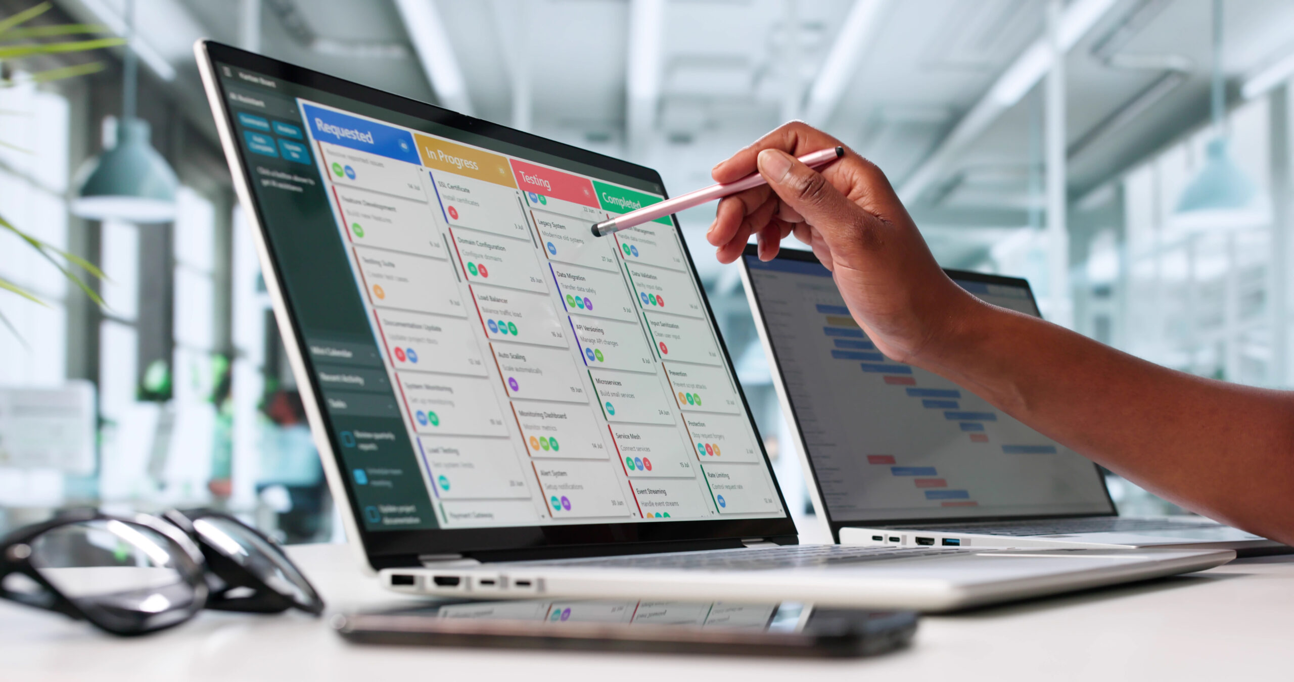 Hand zeigt auf Laptop mit Kanban-Board für den kommunalen Büroalltag.
