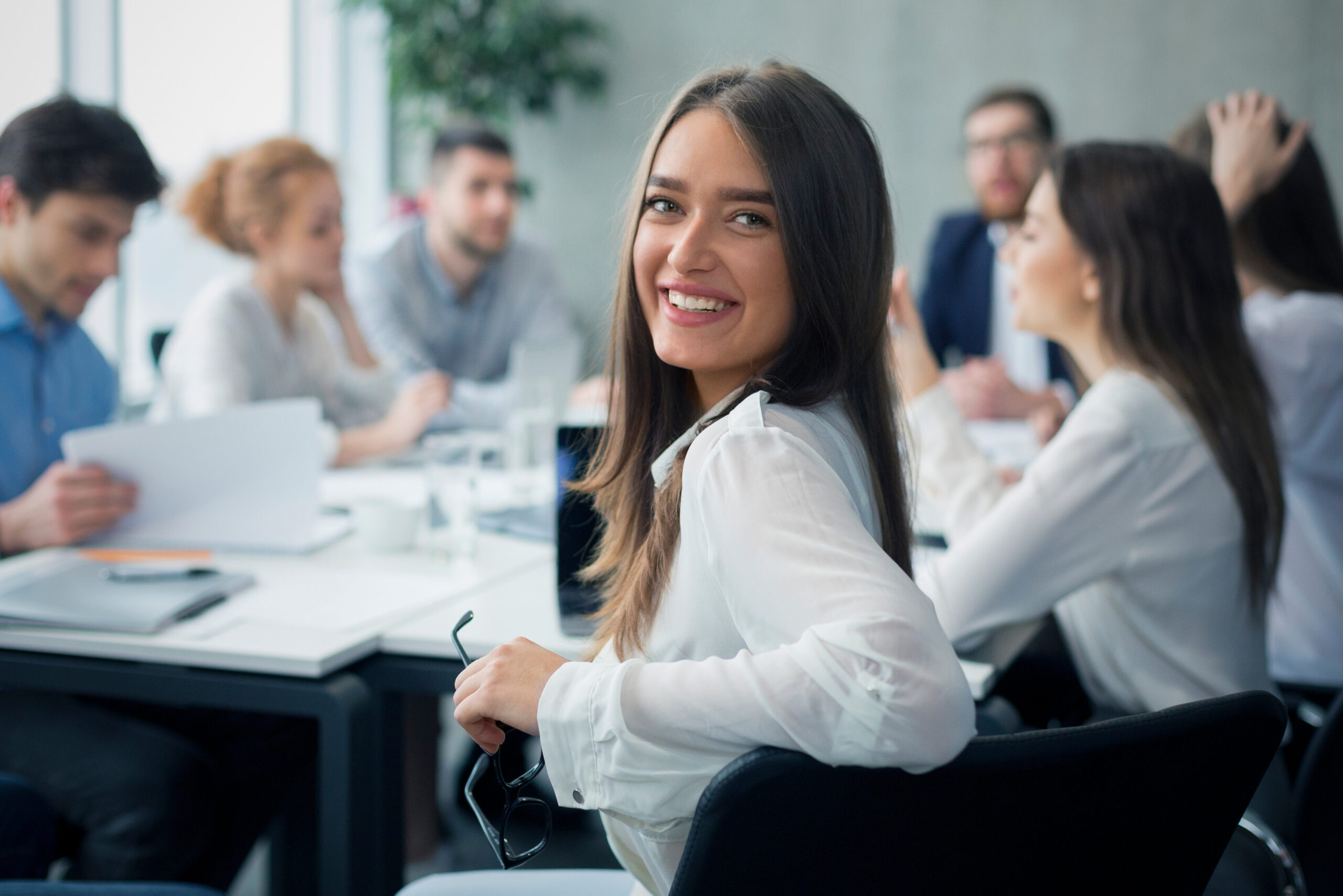 Gremien Mitarbeiterin im weißen Hemd lächelt in Gremiensitzung im modernen Büro.